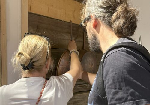 doamna ghid de la muzeul satului îi arată unui nevăzător niște obiecte expuse