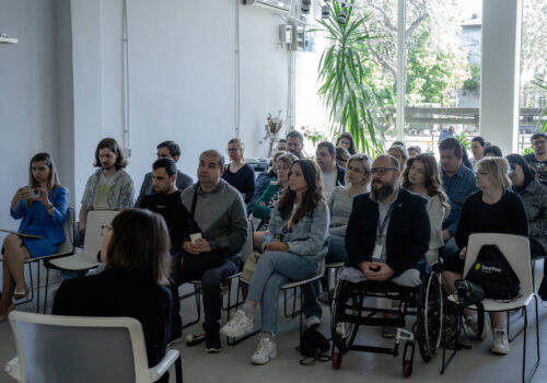 sala plină de persoane cu și fără dizabilități de vedere la lansarea seeyou din bucurești, stau pe scaune.