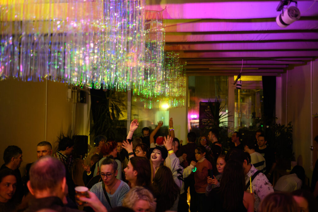 sala mare de la lfi. oamenii dansează cu mâinile ridicate în aer. de tavan, atârnă perdele albe sclipicioase.